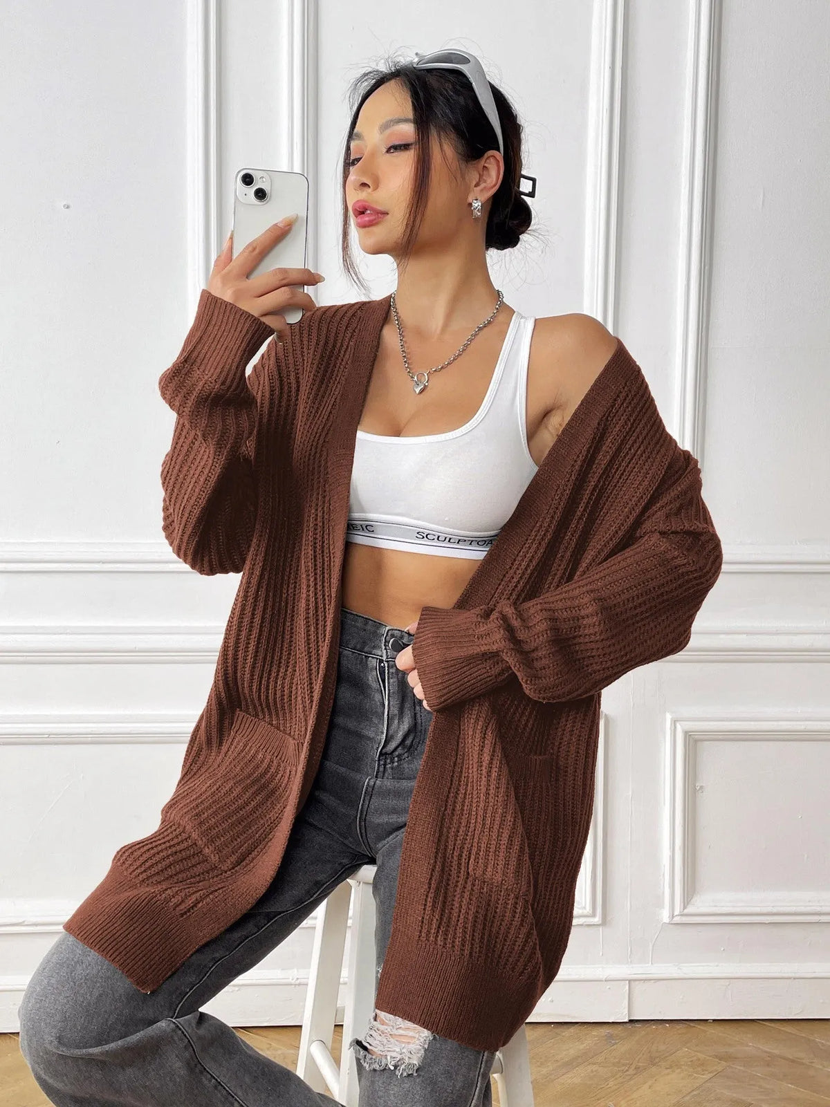 Women's dark green double pocket acrylic cardigan with long sleeves on a hanger.