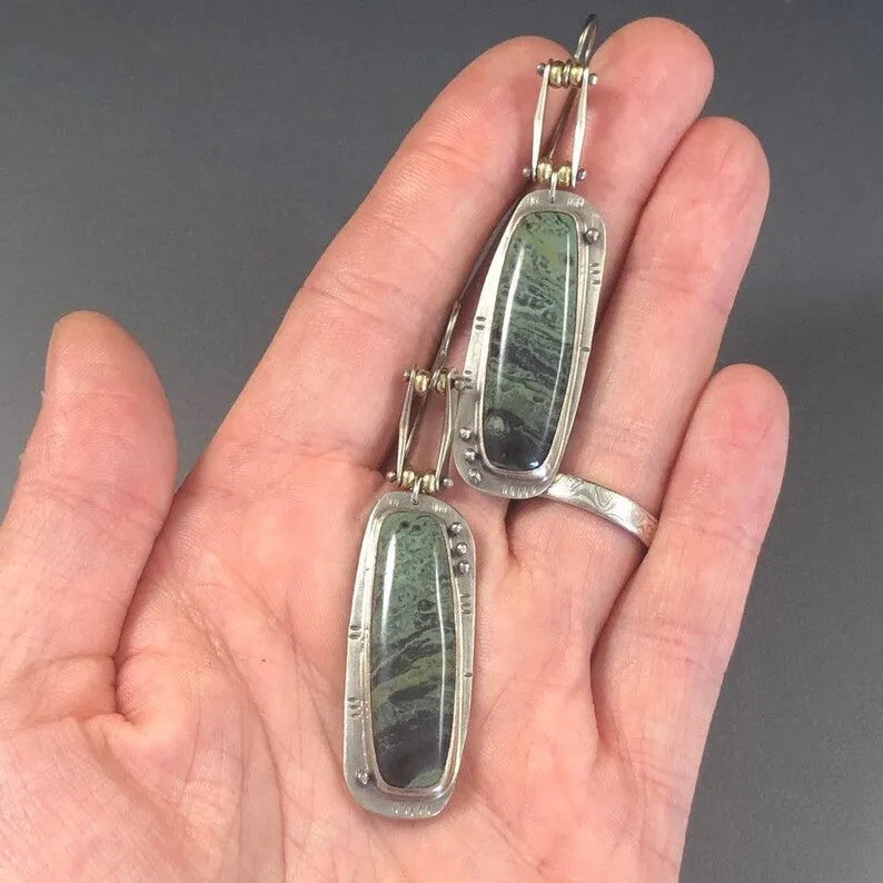 A pair of silver and grey geometric drop earrings with a marble stone pattern on a white background.
