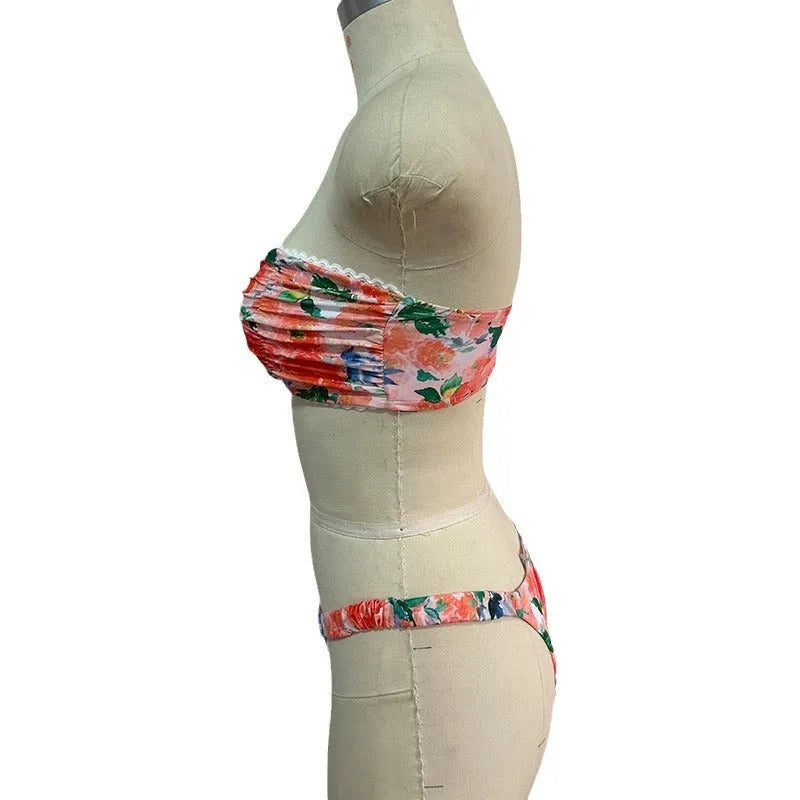 Women's floral print tube top bikini set with lace trim on a blue background.