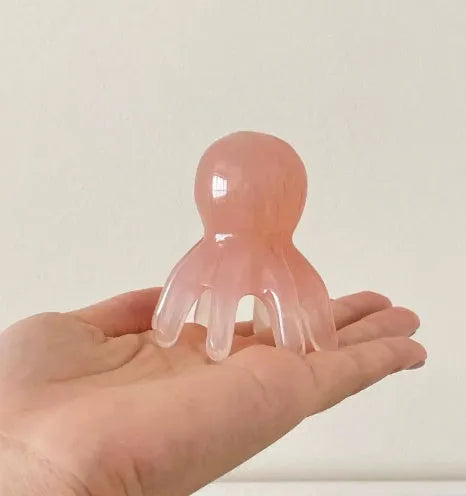 Pink octopus-shaped massage comb made from natural resin with included storage bag for facial meridian therapy