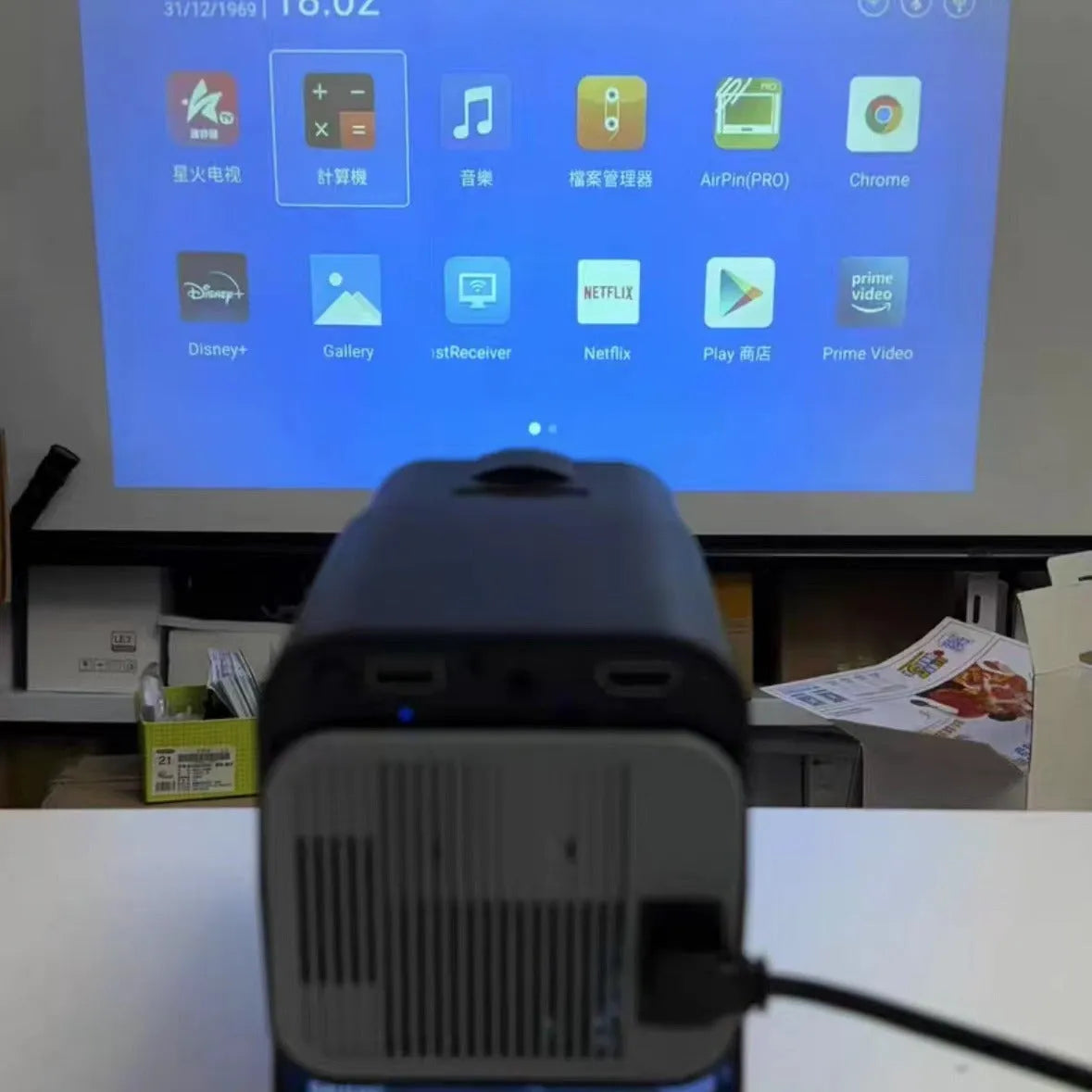 Black 720p wireless home projector on table with international power adaptors for gaming and media projection