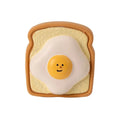 Yellow and green cartoon egg bread shaped latex squeaky toy for dogs on a white background.