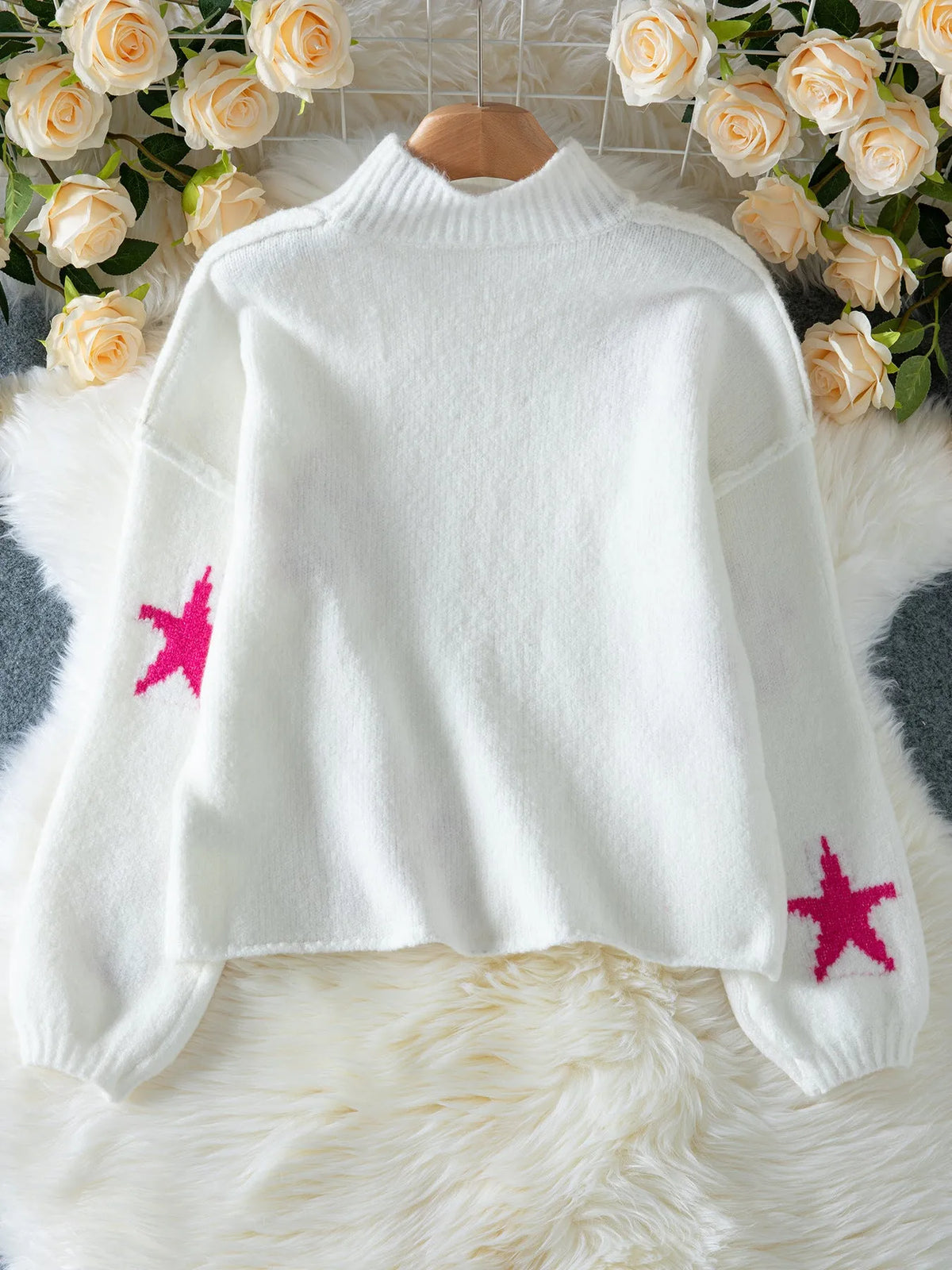 White loose women's turtleneck pullover with a black five-pointed star pattern on the front.