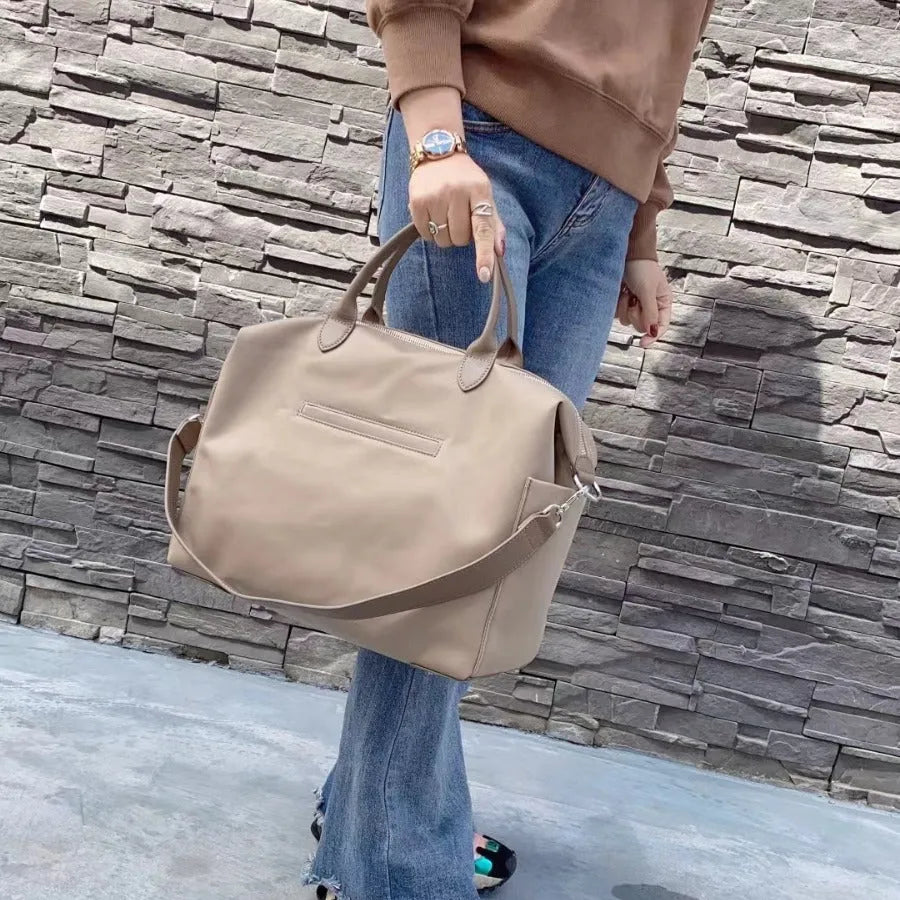 Black nylon waterproof shoulder bag with leather detailing, showing its large capacity.