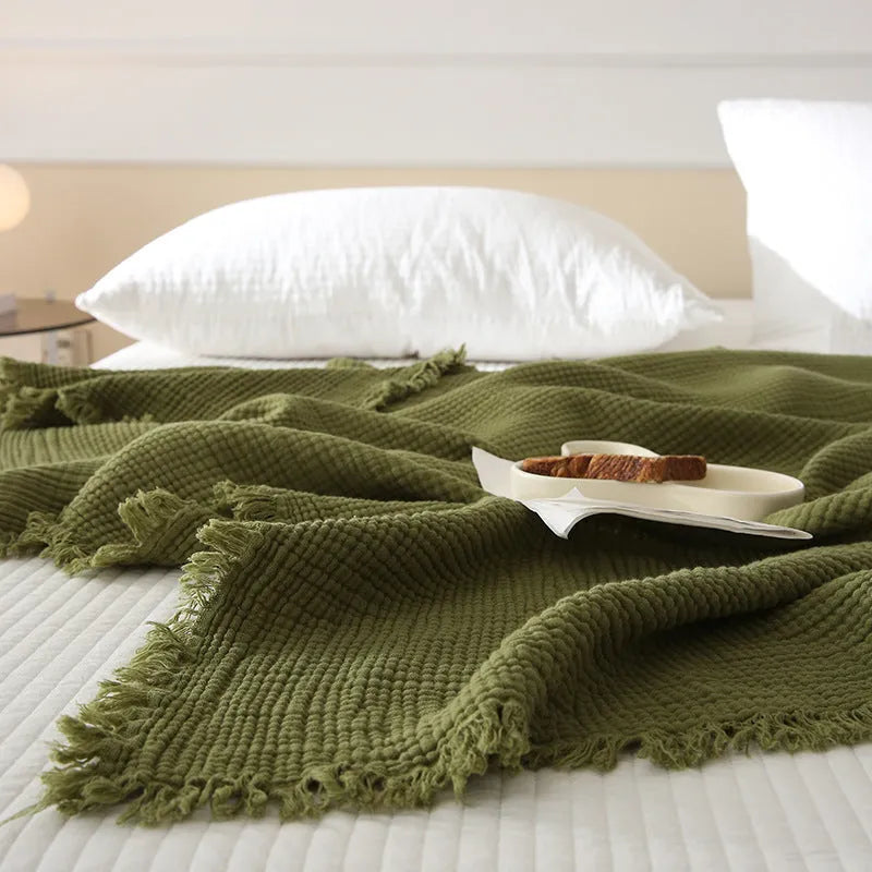 Four-layer cotton gauze tassel blanket in avocado green colour showing tassel detailing