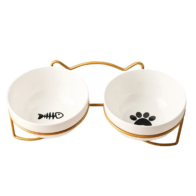 White ceramic cat bowl with cat paw print design sitting in a black iron frame stand