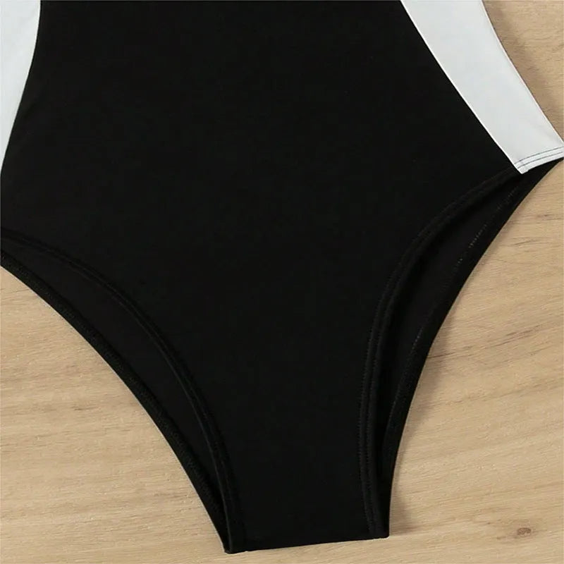 Black and white women's one-piece swimsuit with pearl-decorated spaghetti straps for a slimming fit.