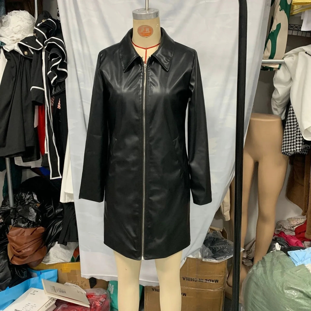 Black women's polyester leather jacket on a hanger, showing medium length and long sleeves.