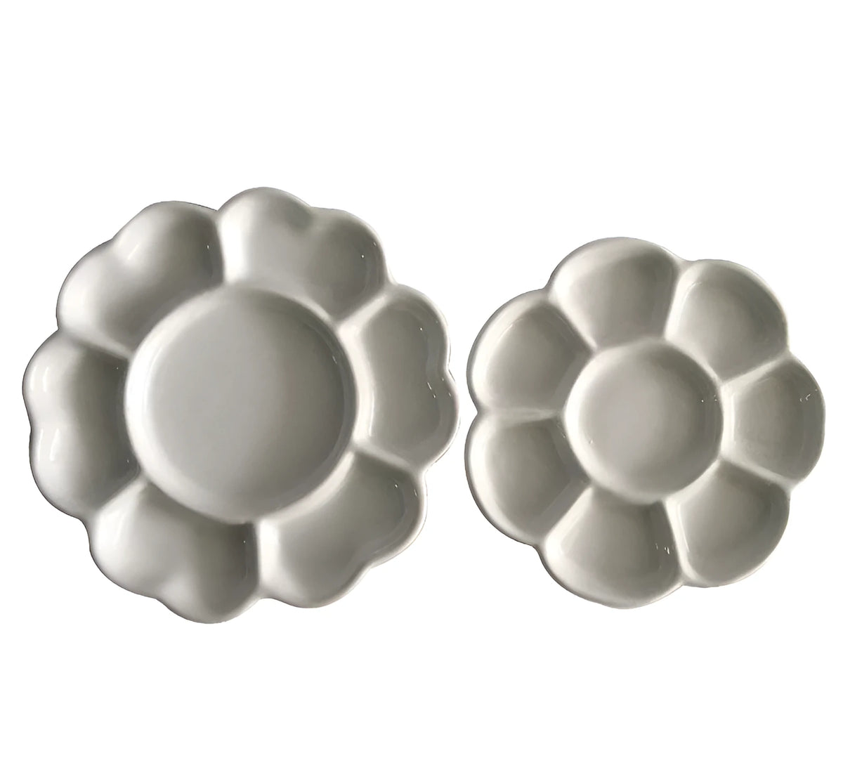 White ceramic plum blossom shaped artist's paint palette on a wooden table.