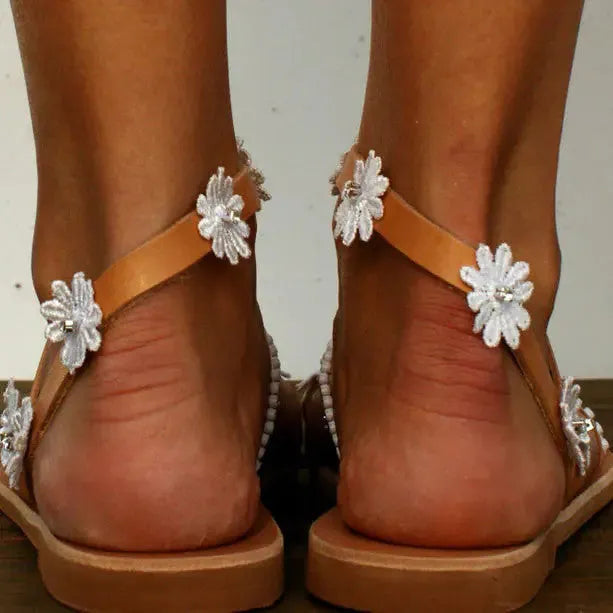 Brown flat casual sandals with a flower decoration and ethnic pattern on the upper.