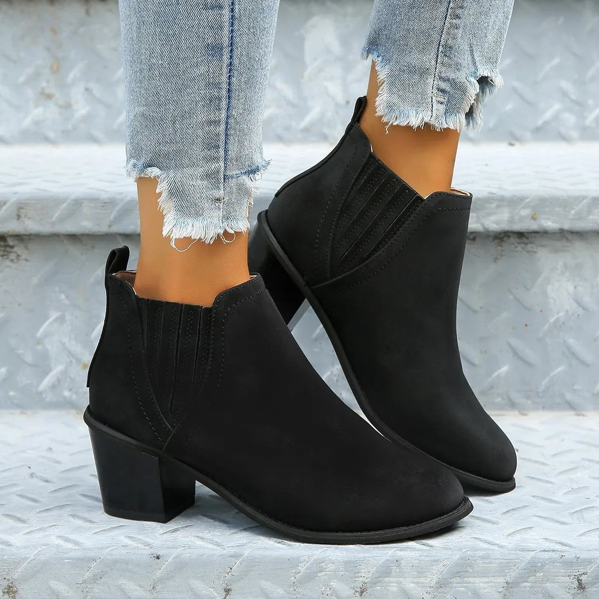 Women's black ankle boots with pointed toes and thick square heels on a solid background