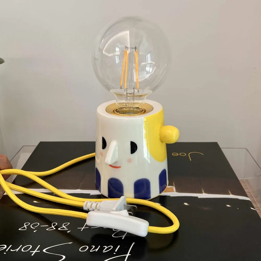 Handmade ceramic table lamp with white ball headlight design on wooden surface