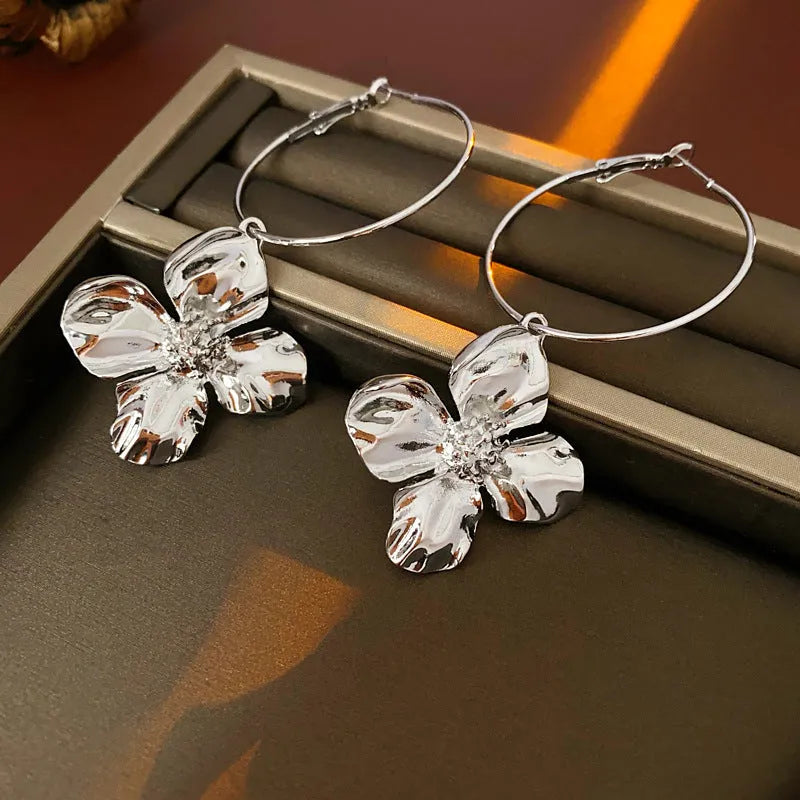 A pair of silver needle metal flower earrings with a geometric design in a gold or silver colour.