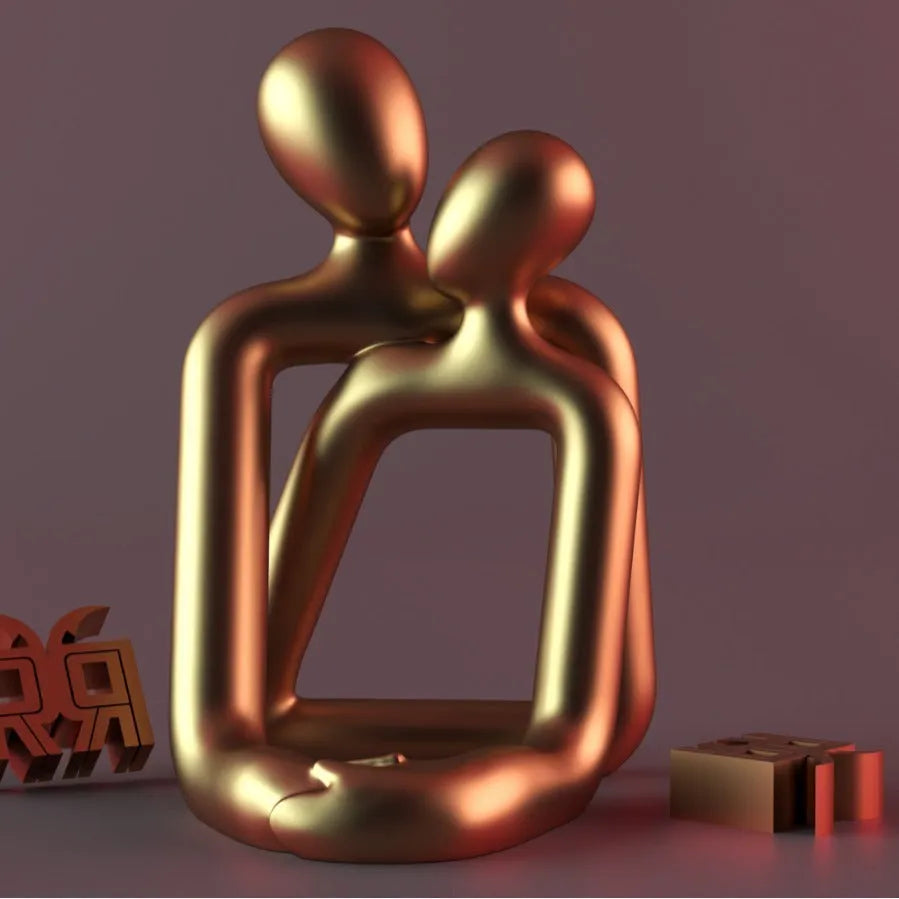 Modern heartwarming couple resin statue in milky white or gold colour on a wooden desk.