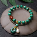 Handmade malachite and red agate bead bracelet with 7-8mm barrel beads on a wrist.