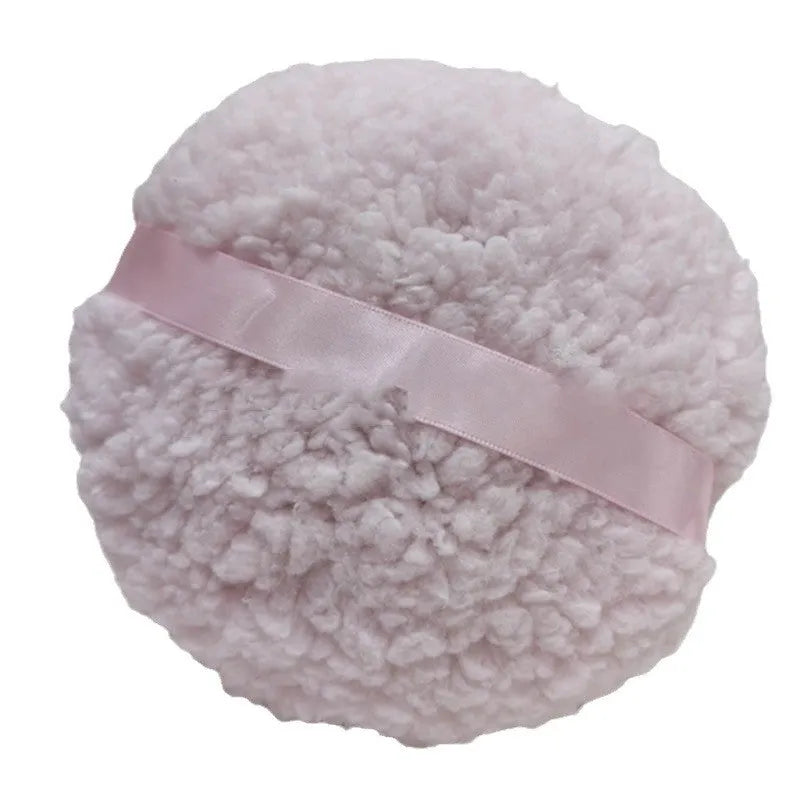 Oversized rectangular plush powder puff in skin colour on a pink background