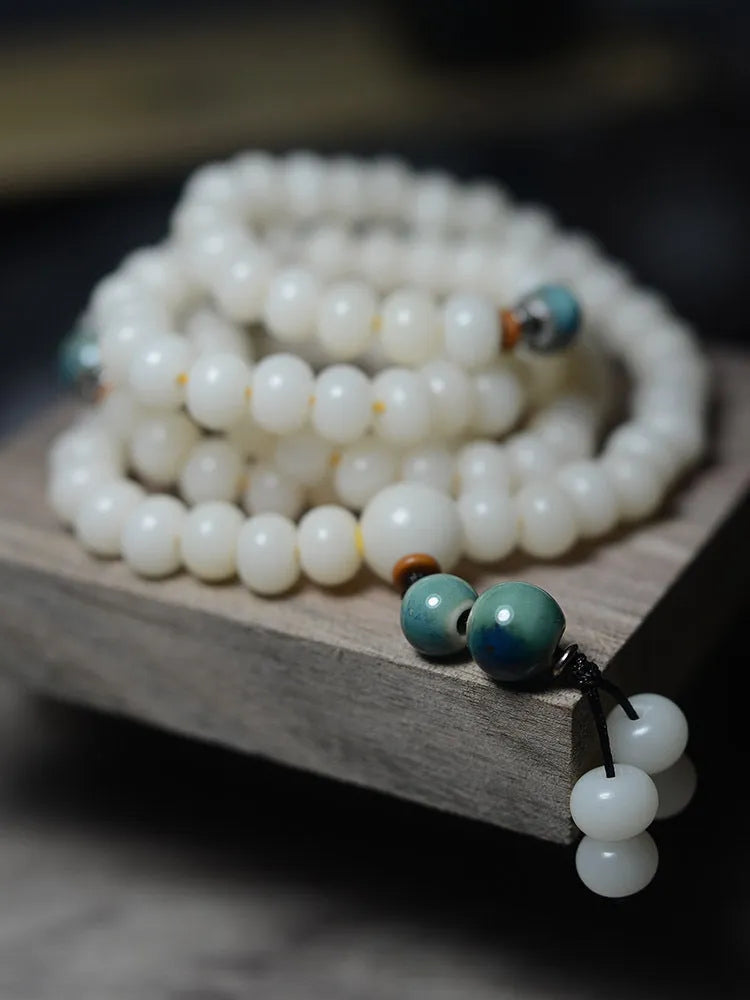 White jade bodhi root bracelet with 108 flat round beads in two sizes on a wrist.