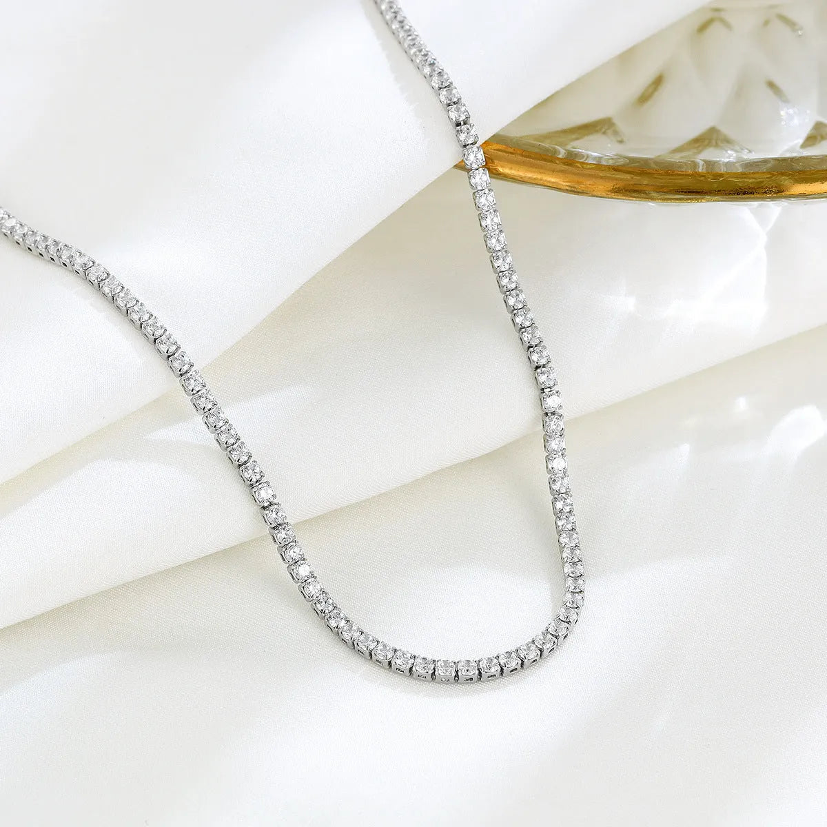 Close-up of a women's sterling silver necklace with round diamond-cut elements on a polished chain.