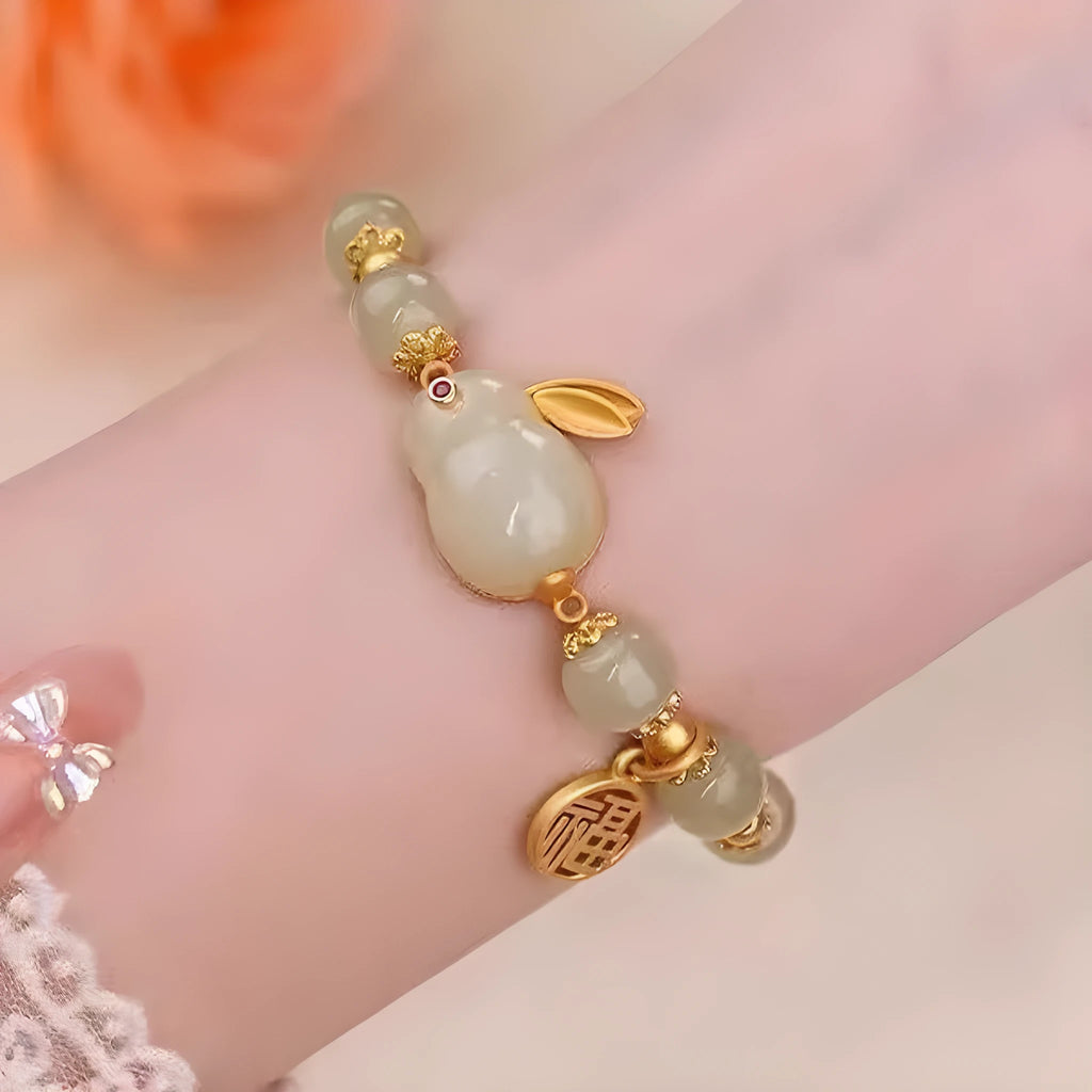 Close-up of a black women's bracelet with a green jade fu character charm and a metal hare pendant.
