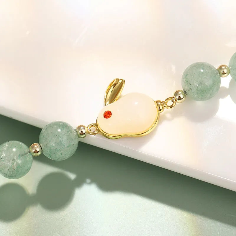 Rabbit charm bracelet with green aventurine and strawberry quartz stones on a gold or copper chain.