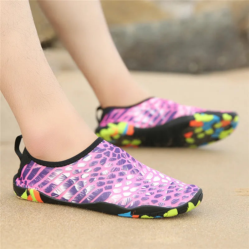 Pair of blue Lycra beach wading shoes with EVA midsole on a sandy beach background.