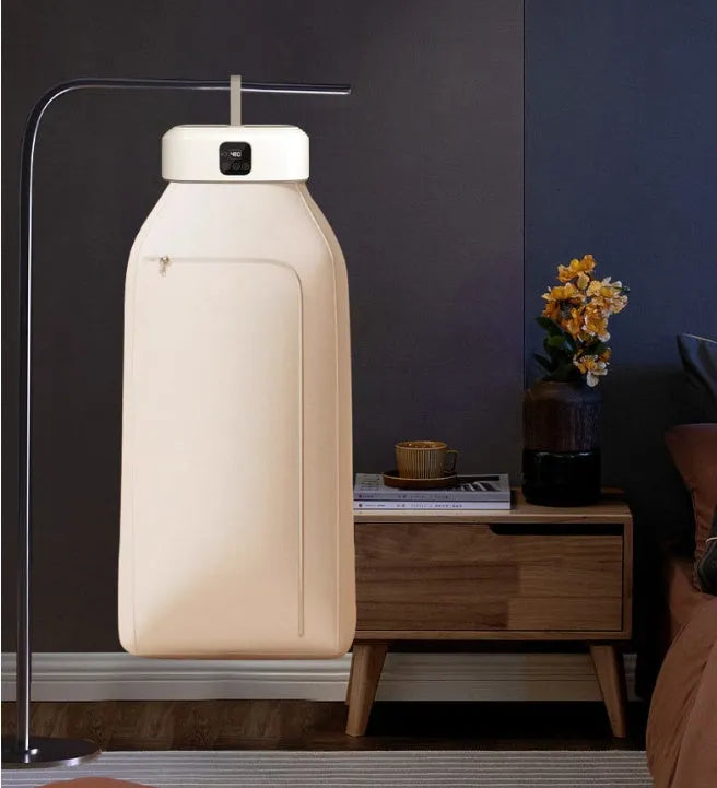 White cylindrical compact electric clothes dryer with remote control on a table.
