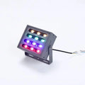 Silver aluminium alloy outdoor LED spotlight projecting multicoloured light onto a tree.