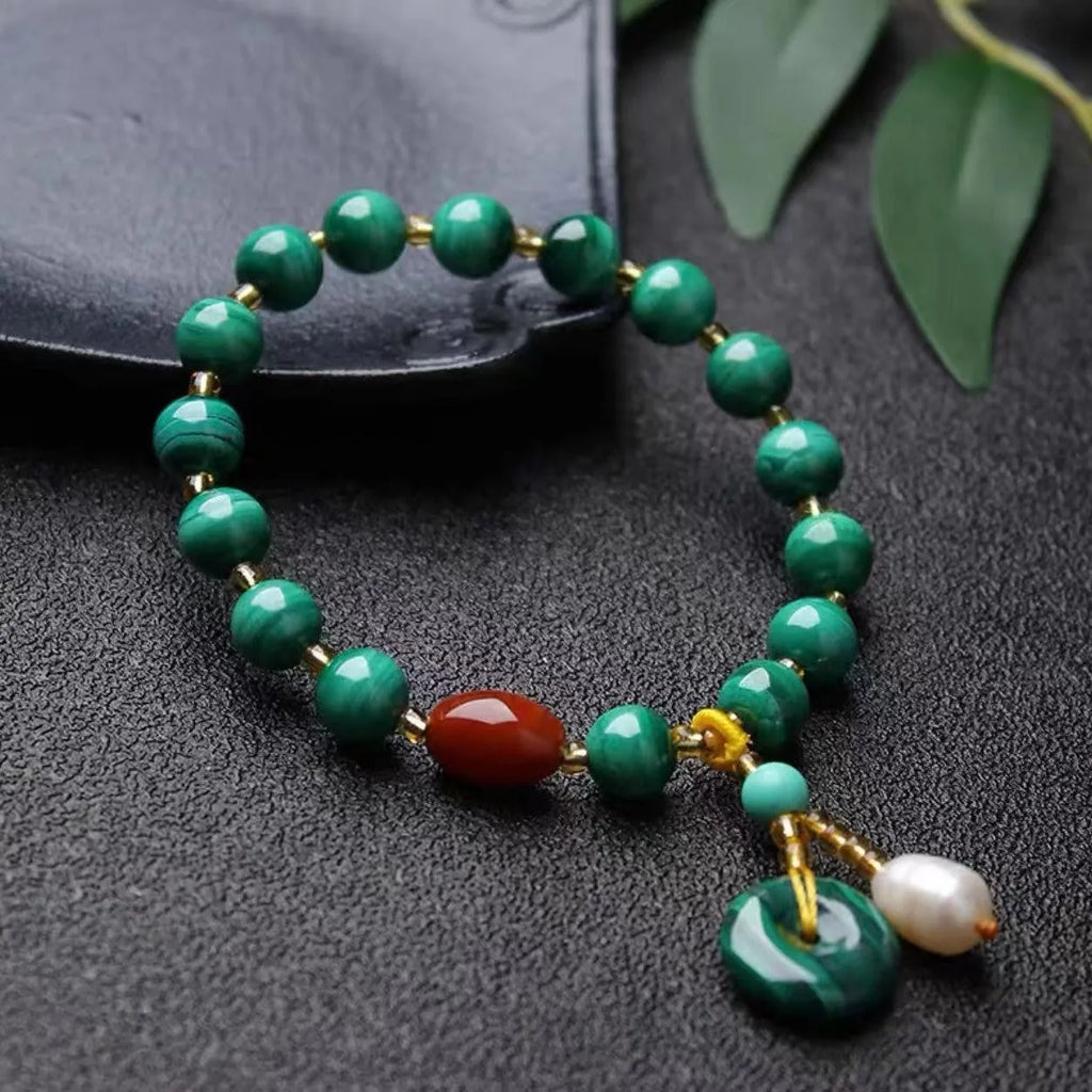 Handmade malachite and red agate bead bracelet with 7-8mm barrel beads on a wrist.
