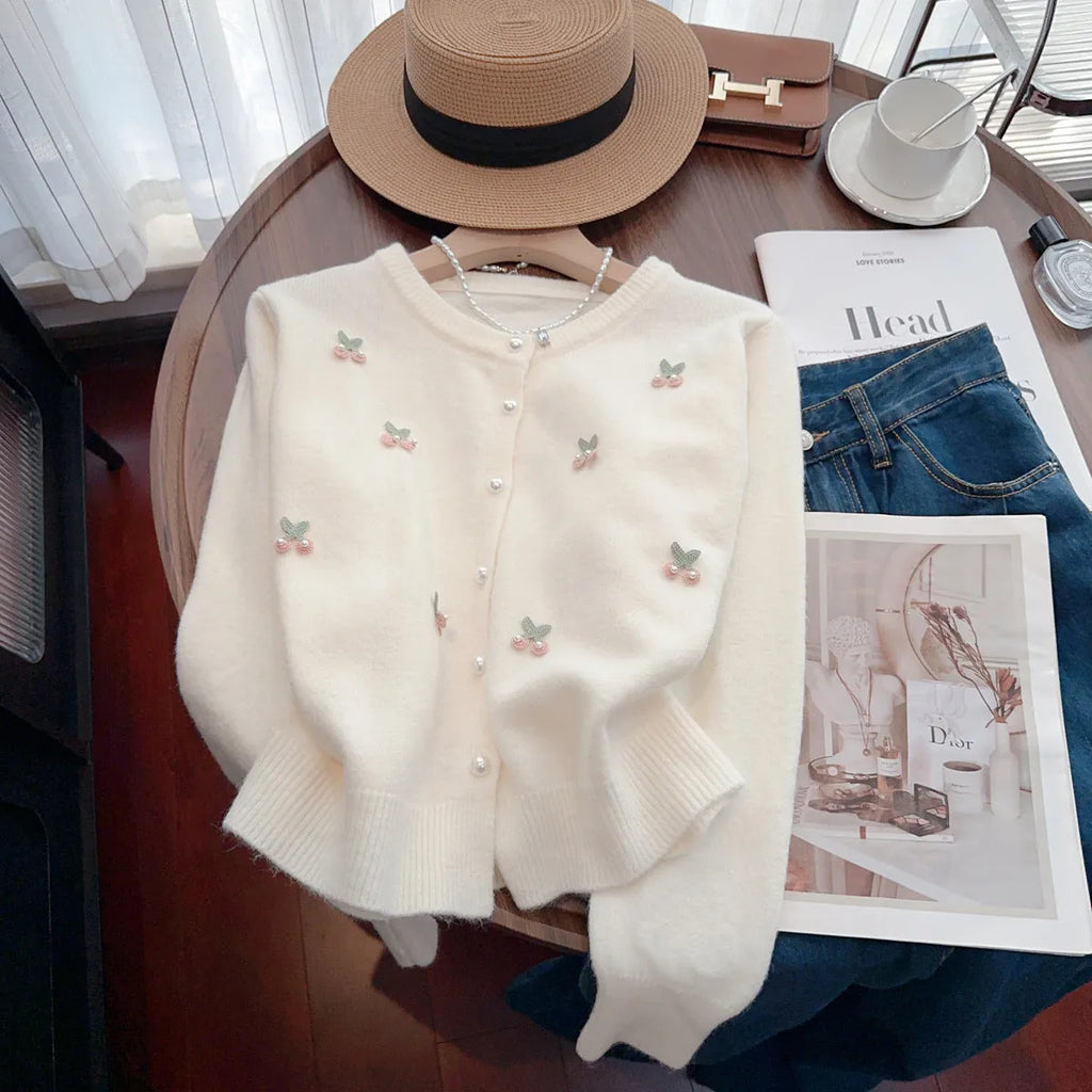 A pink cashmere blend ladies cardigan with beaded details, shown on a hanger.