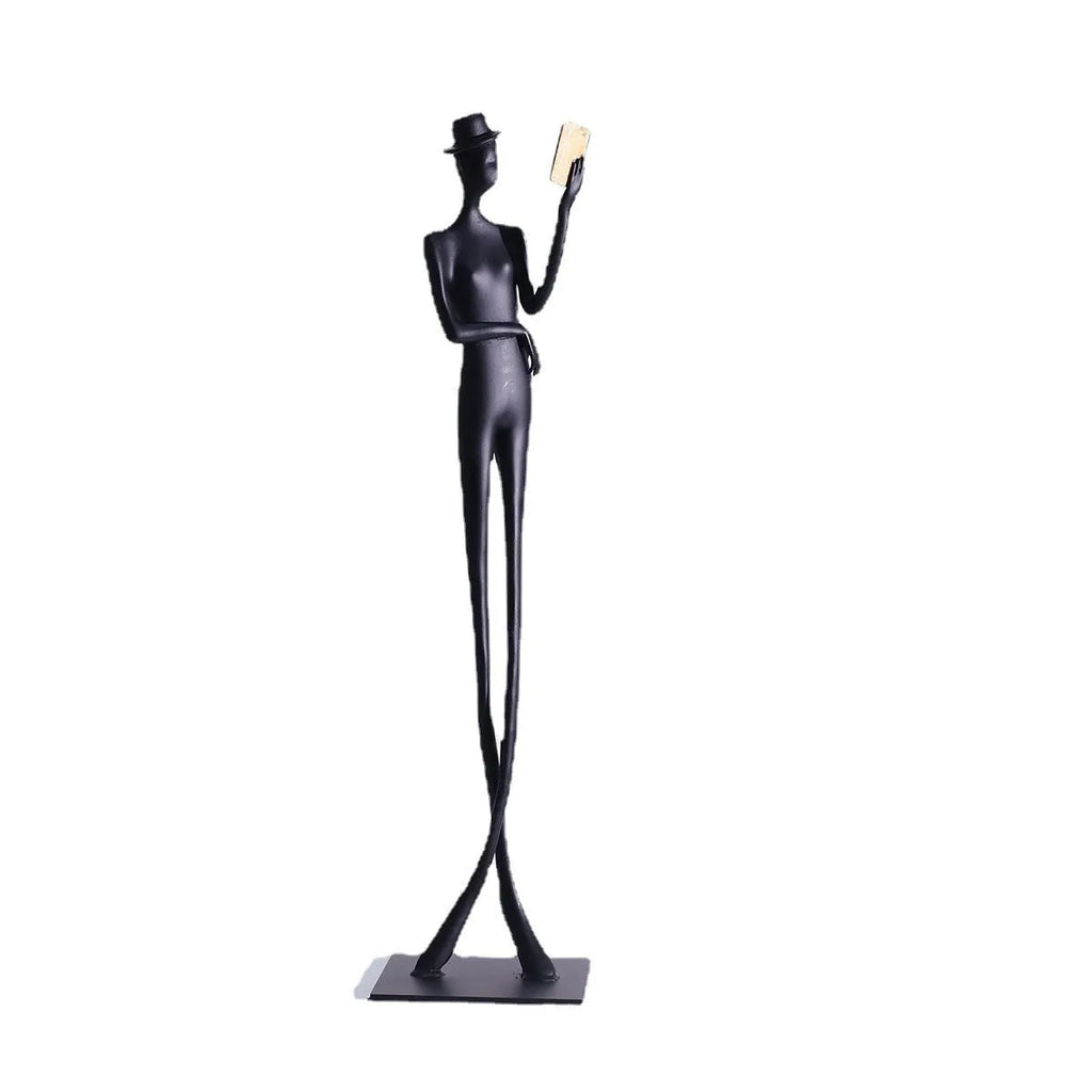 Black aluminium desktop sculpture of a woman reading, measuring 12cm wide by 51cm tall.