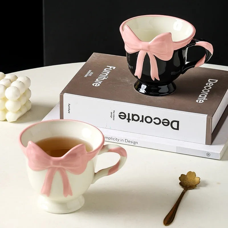 Cute white ceramic mug with a black heart bow design and printed handle ornament.