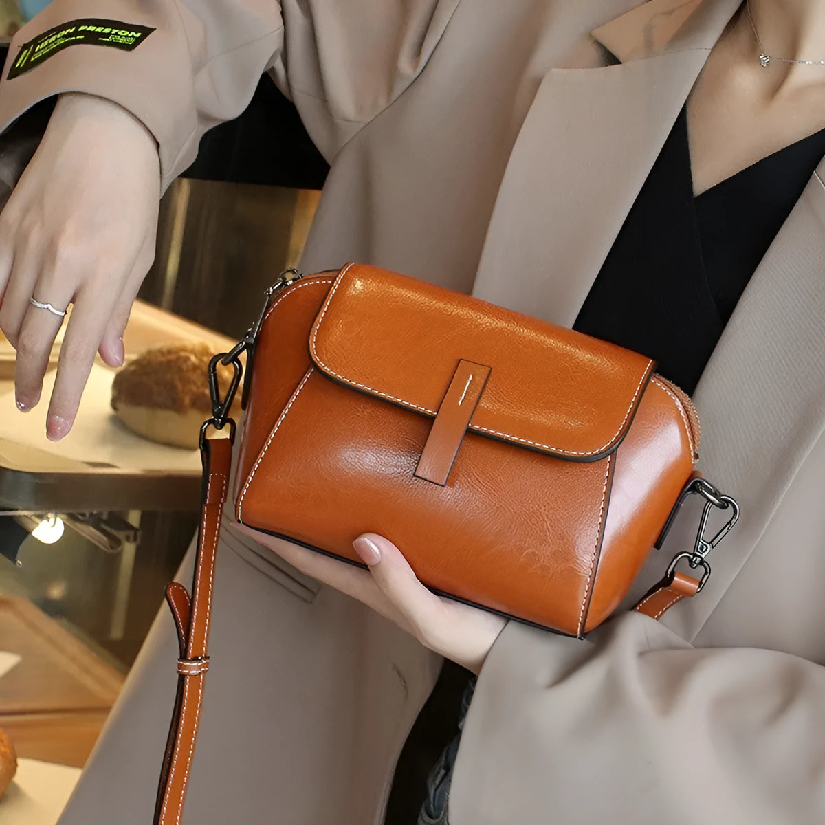 Women's brown shell-shaped messenger bag made of oil wax leather with a cross-body strap.