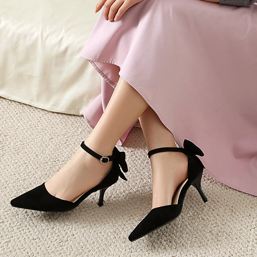 Women's black pointed-toe high heels with bowknot detail and buckle fastening