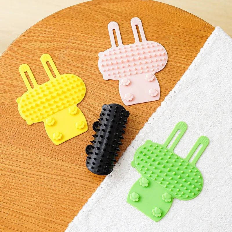 Silicone cat grooming comb with adjustable strap attached to table leg for hair removal and scratching relief