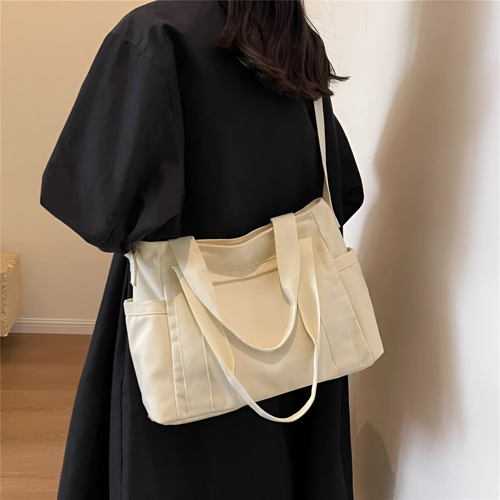 Women's solid colour canvas shoulder bag showing interior mobile phone compartment and exterior sandwich pocket
