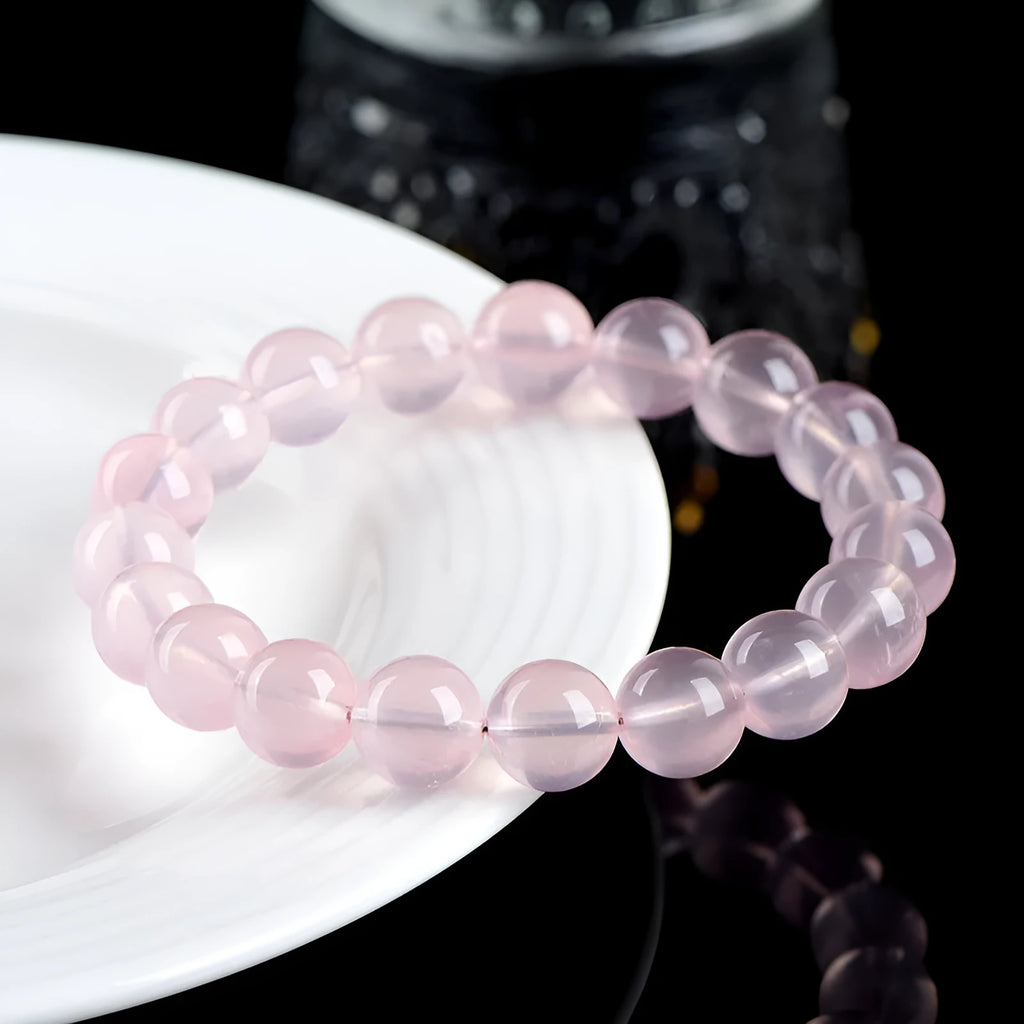Close-up of a women's bracelet with polished round pink crystal beads on a single strand, showing smooth surface and sparkle.