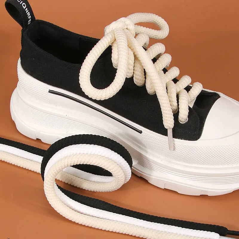 Round white woven shoelace with 10mm diameter next to a beige and black lace on a grey background.