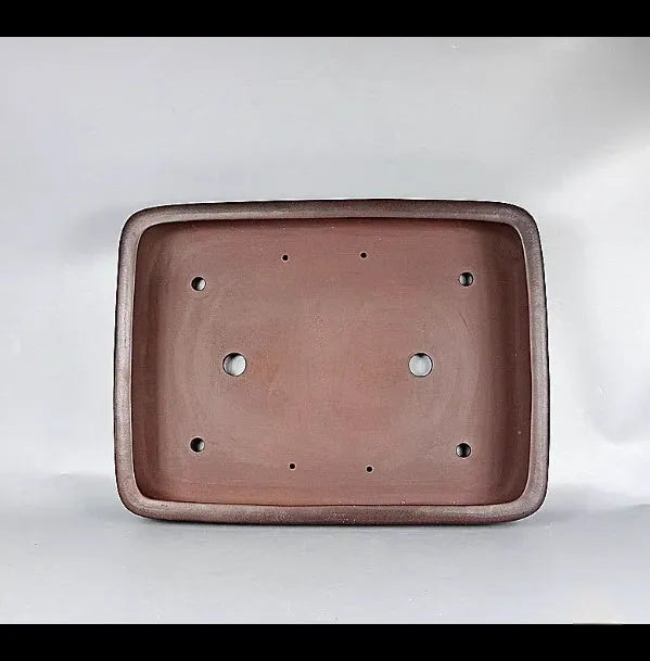 Handmade antique rectangular purple clay flower pot on a wooden surface.