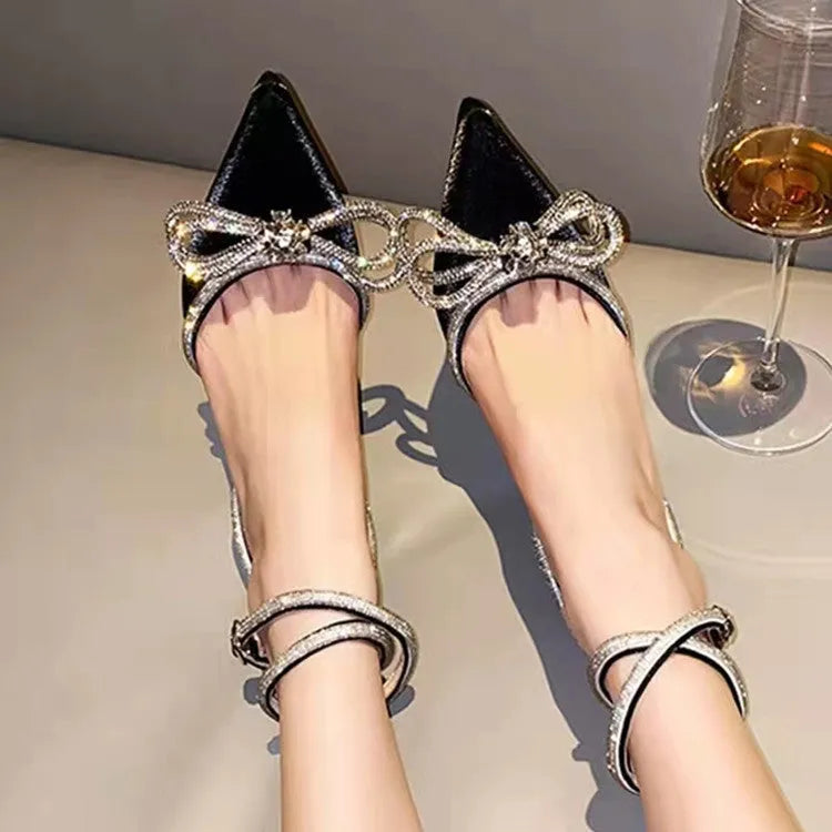 Women's black stiletto heel sandals with a silk bandage wrap back and buckle fastening, showing pointed toe.