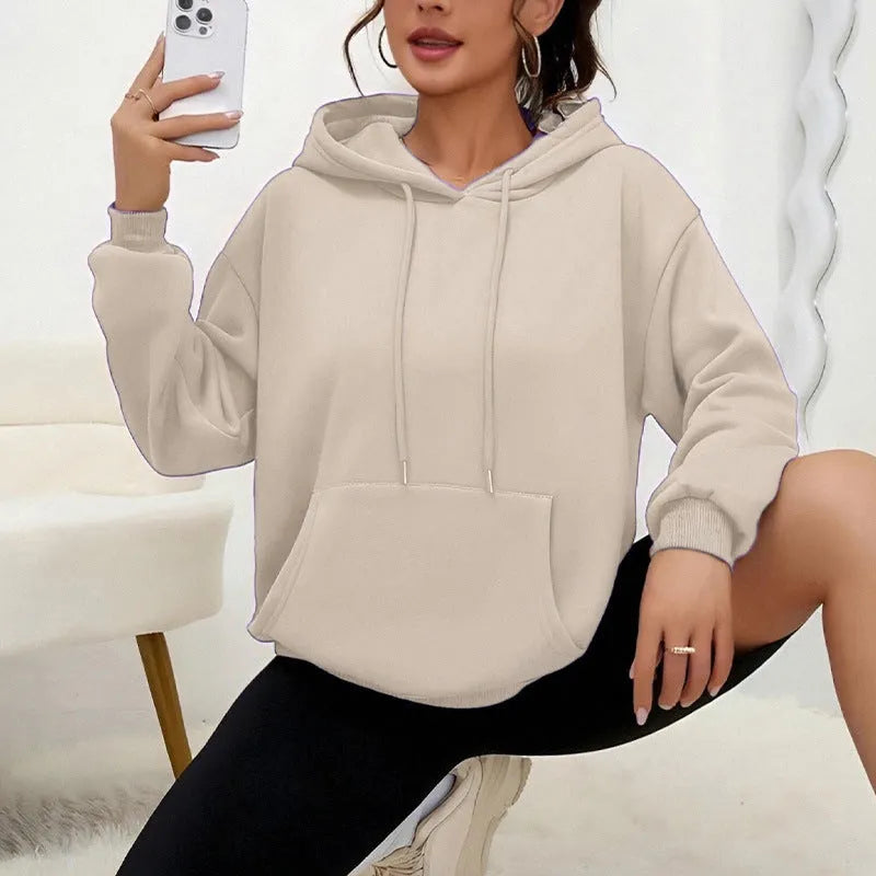 A woman wearing a loose grey drawstring hooded sweatshirt with a front pocket, showing the relaxed fit.