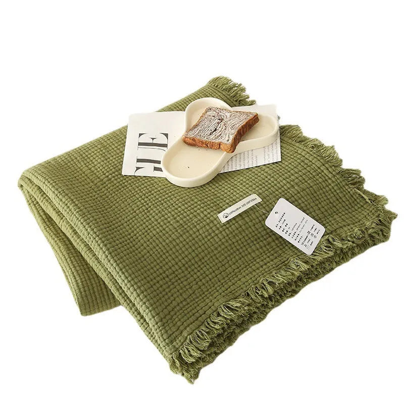 Four-layer cotton gauze tassel blanket in avocado green colour showing tassel detailing