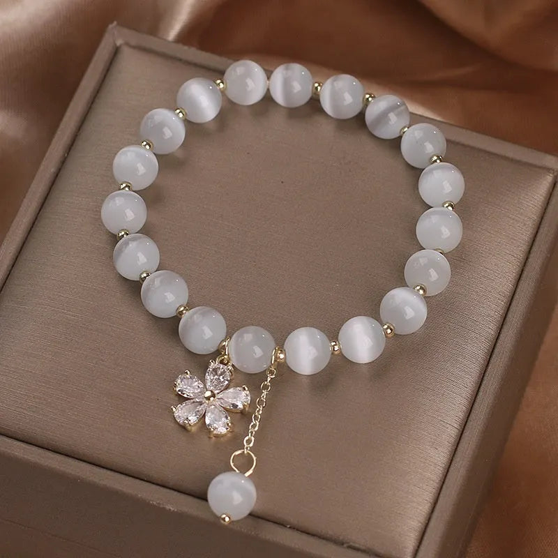Women's white cat's eye crystal bracelet with flower tassel detailing and safety buckle pendant