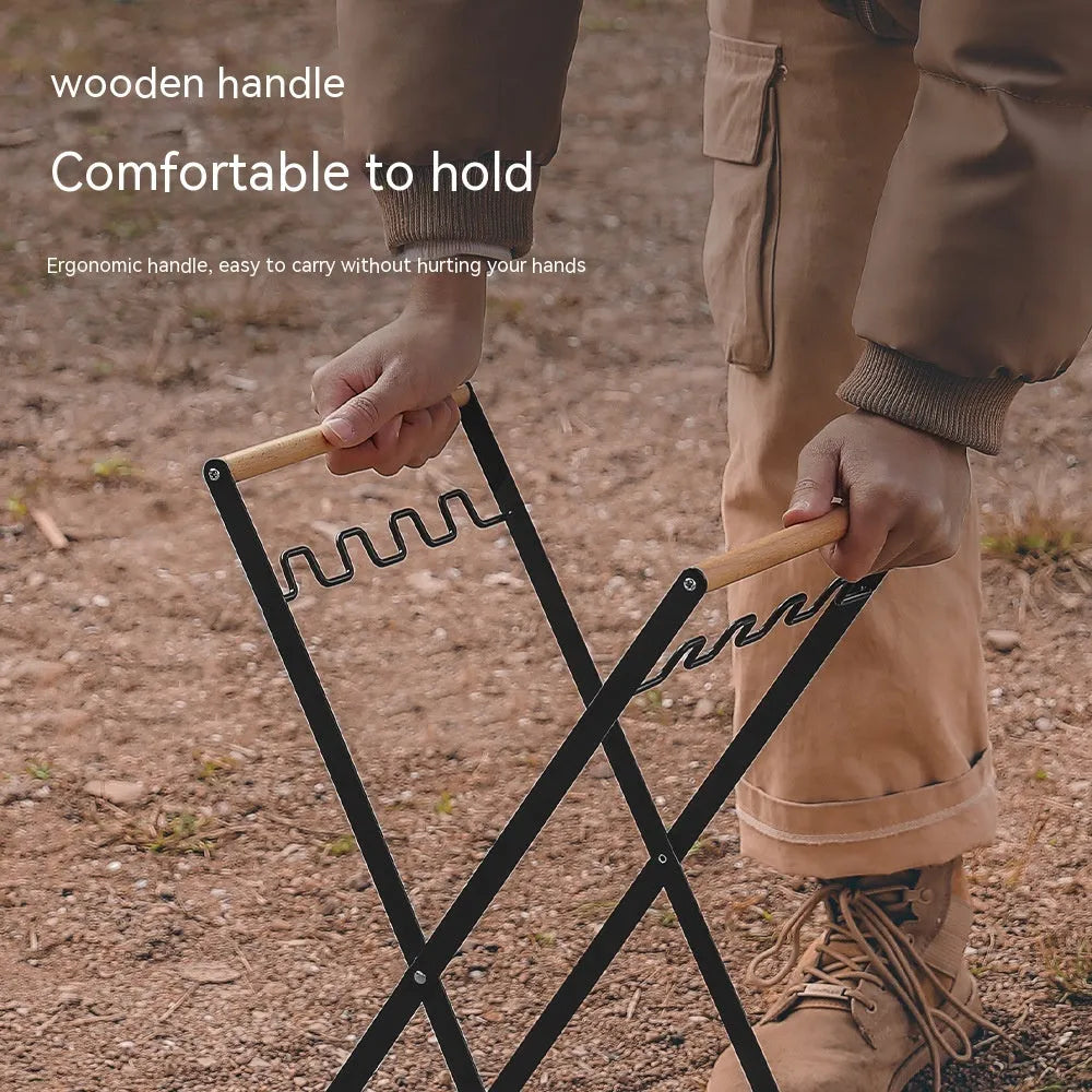 Black folding iron trash rack with wooden handle holding a bin bag outdoors.
