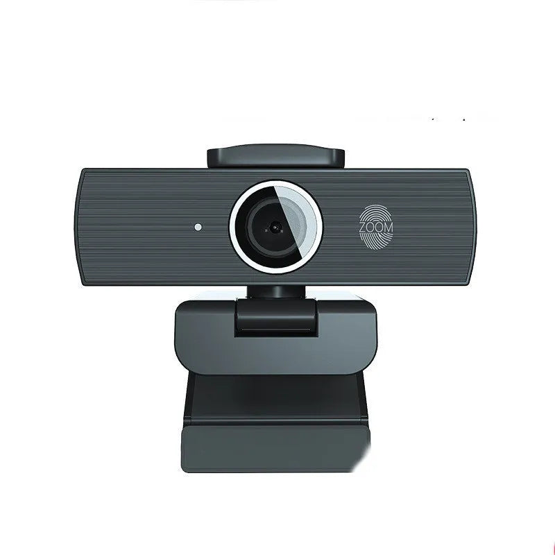 Black ABS USB web camera with magnetic privacy cover on a desk next to a laptop.