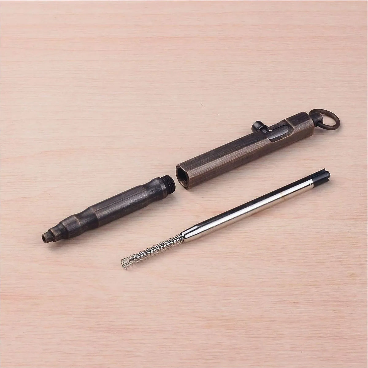 Brass tactical pen with hexagonal bolt design and machine gun aesthetic on a dark background.