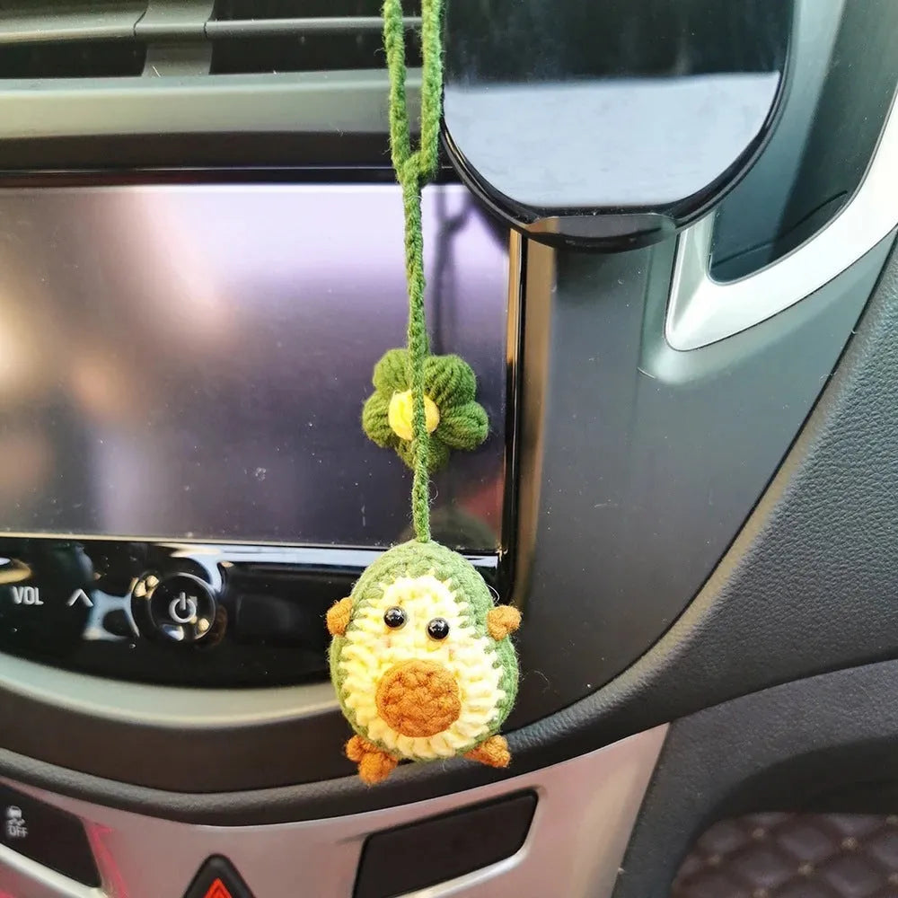 Handmade crocheted avocado-shaped car pendant with rainbow pattern, hanging.
