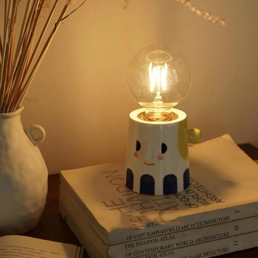 Handmade ceramic table lamp with white ball headlight design on wooden surface