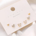 Three pairs of heart-shaped women's earrings in gold, black, black and white, and pink colours