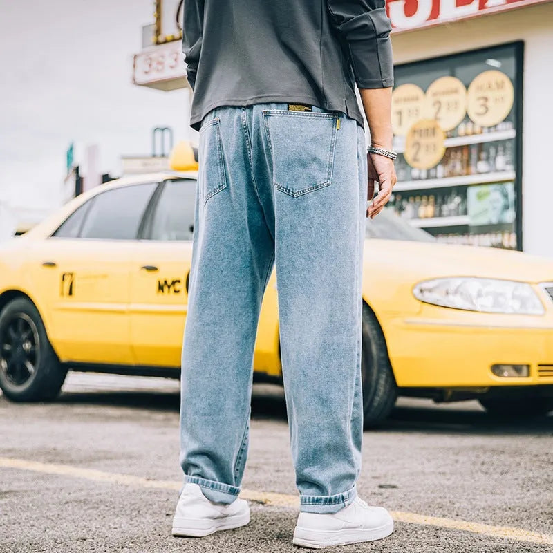 Men's loose straight blue jeans on hanger showing mid-waist design and straight leg cut