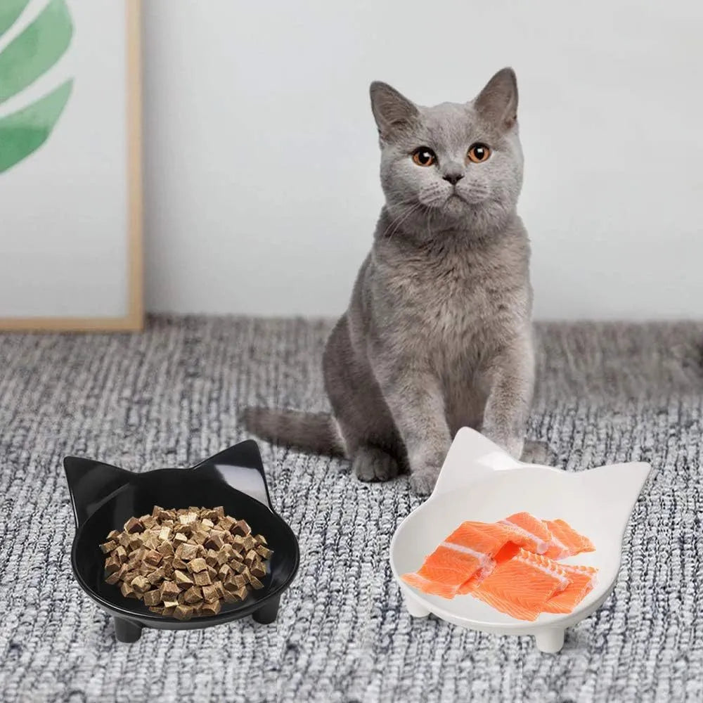 Set of four white shallow melamine pet bowls with black non-slip rubber bases on a table.